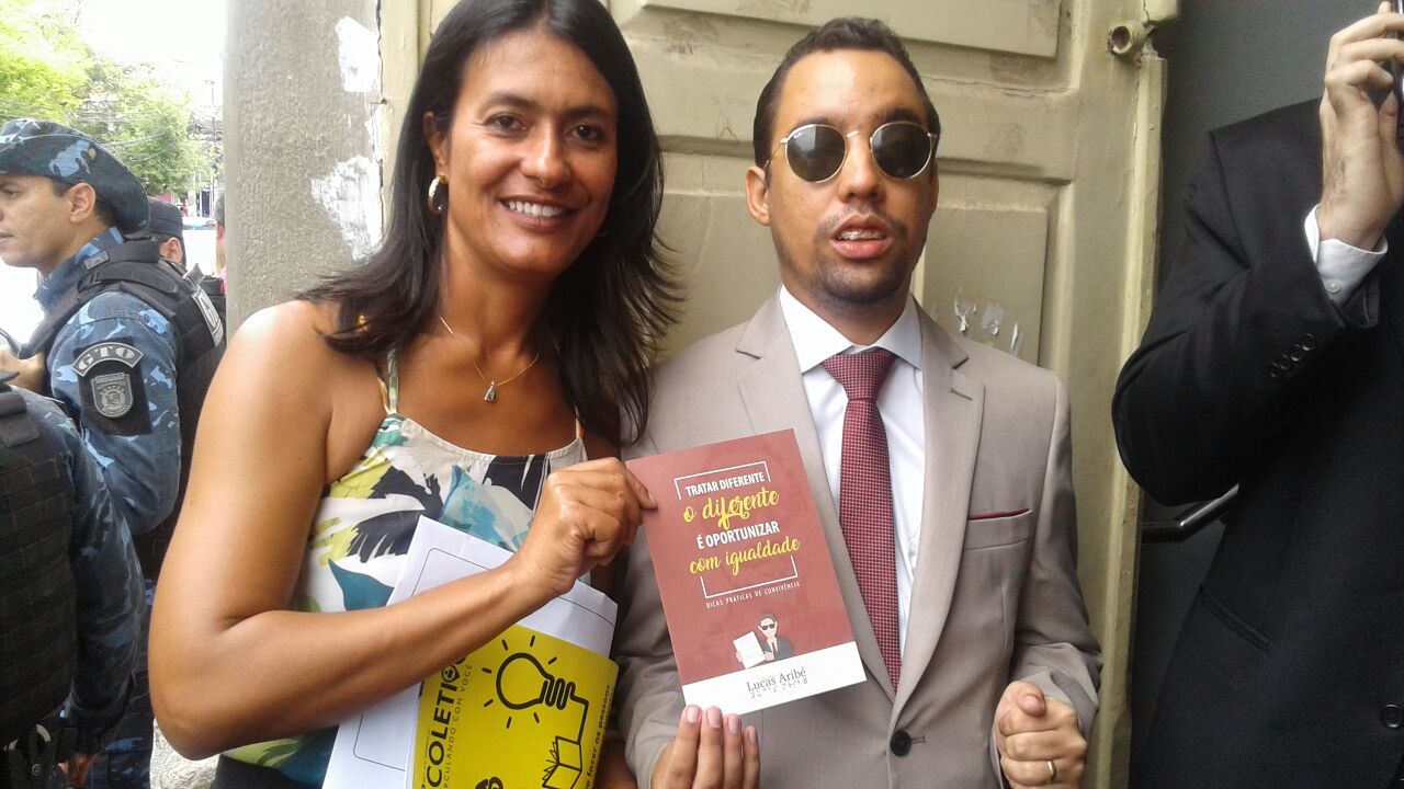 Vereador Lucas Aribé (PSB) ao lado da vice-prefeita, Eliane Aquino (PT). Os dois segurando a cartilha “Tratar Diferente o Diferente é Oportunizar com Igualdade: Dicas Práticas de Convivência”. 