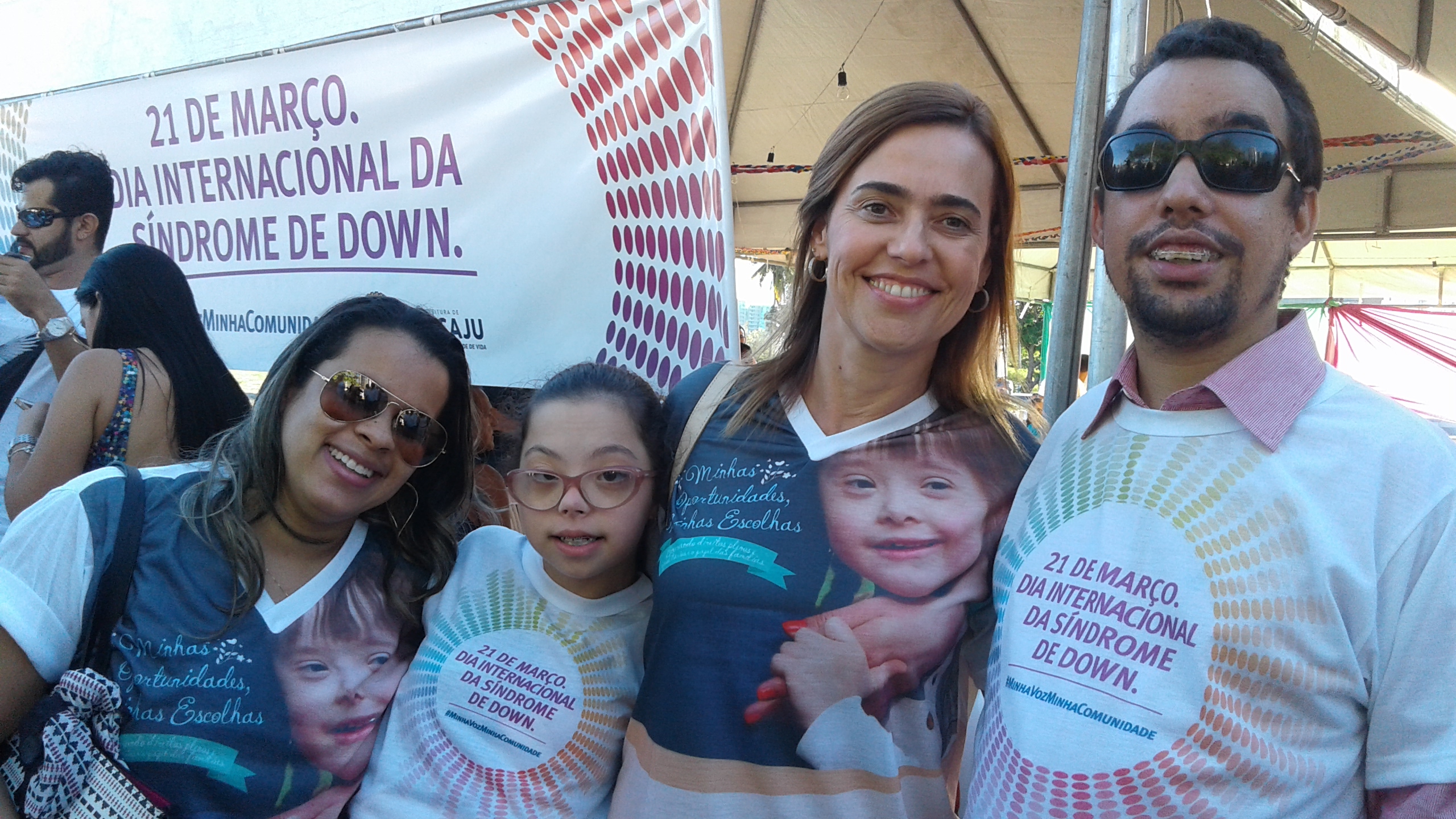 Vereador Lucas Aribé sorrindo em pé ao lado de uma criança que possui Síndrome de Down