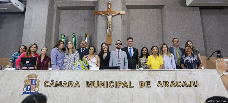 Vereador Lucas Aribé em pé rodeado de vereadores e participantes da Sessão Especial