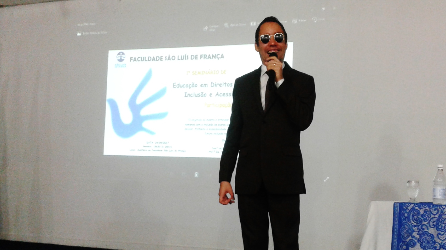 Vereador Lucas Aribé em pé segurando o microfone ao tempo que fala para os alunos da Faculdade São Luís de França
