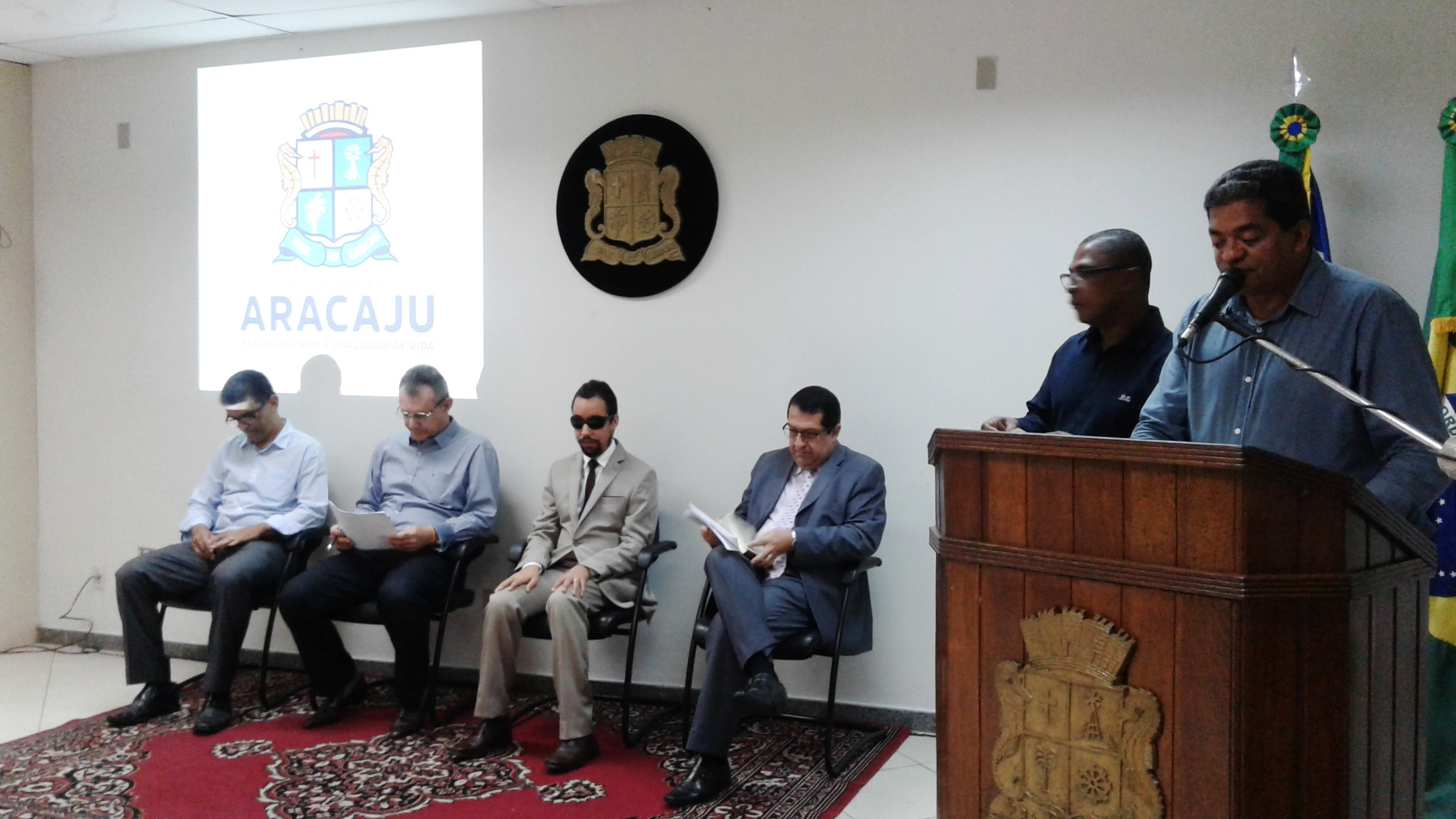 Vereador Lucas Aribé na sala de reuniões do Centro Administrativo de Aracaju sentado ao lado dos gestores municipiais