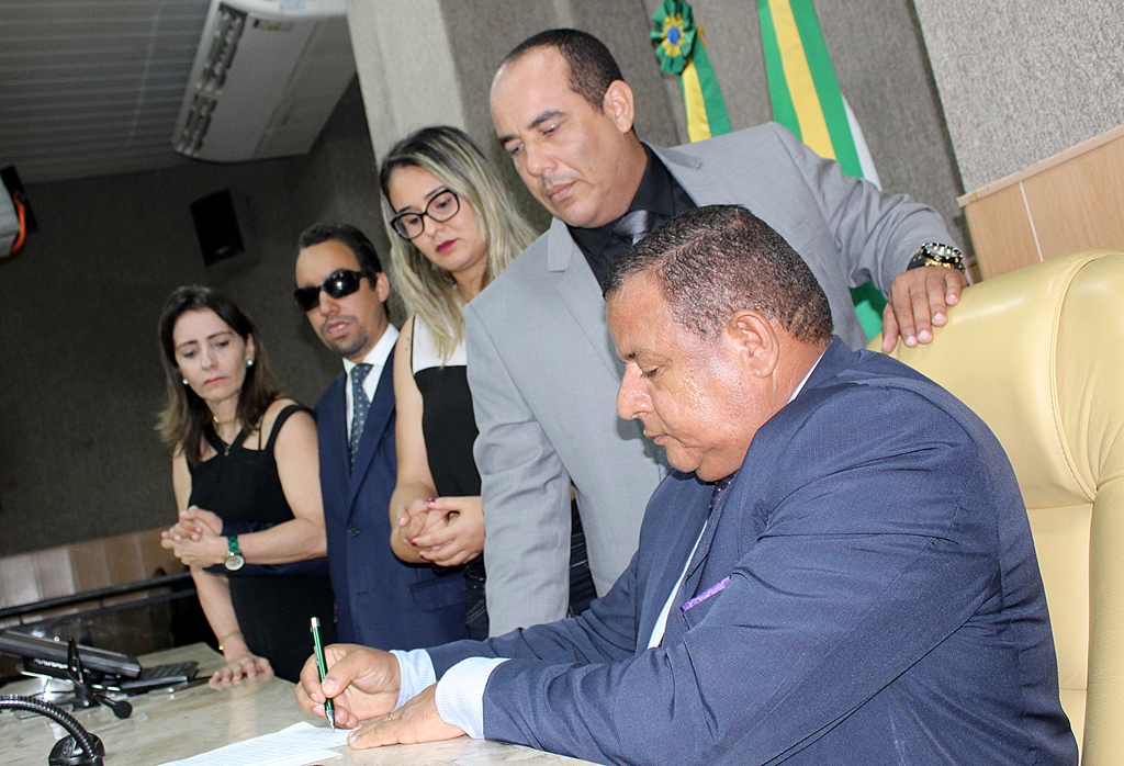 #PRaCegoVer - Presidente da sessão, Américo de Deus assina ata ao lado dos colegas parlamentares