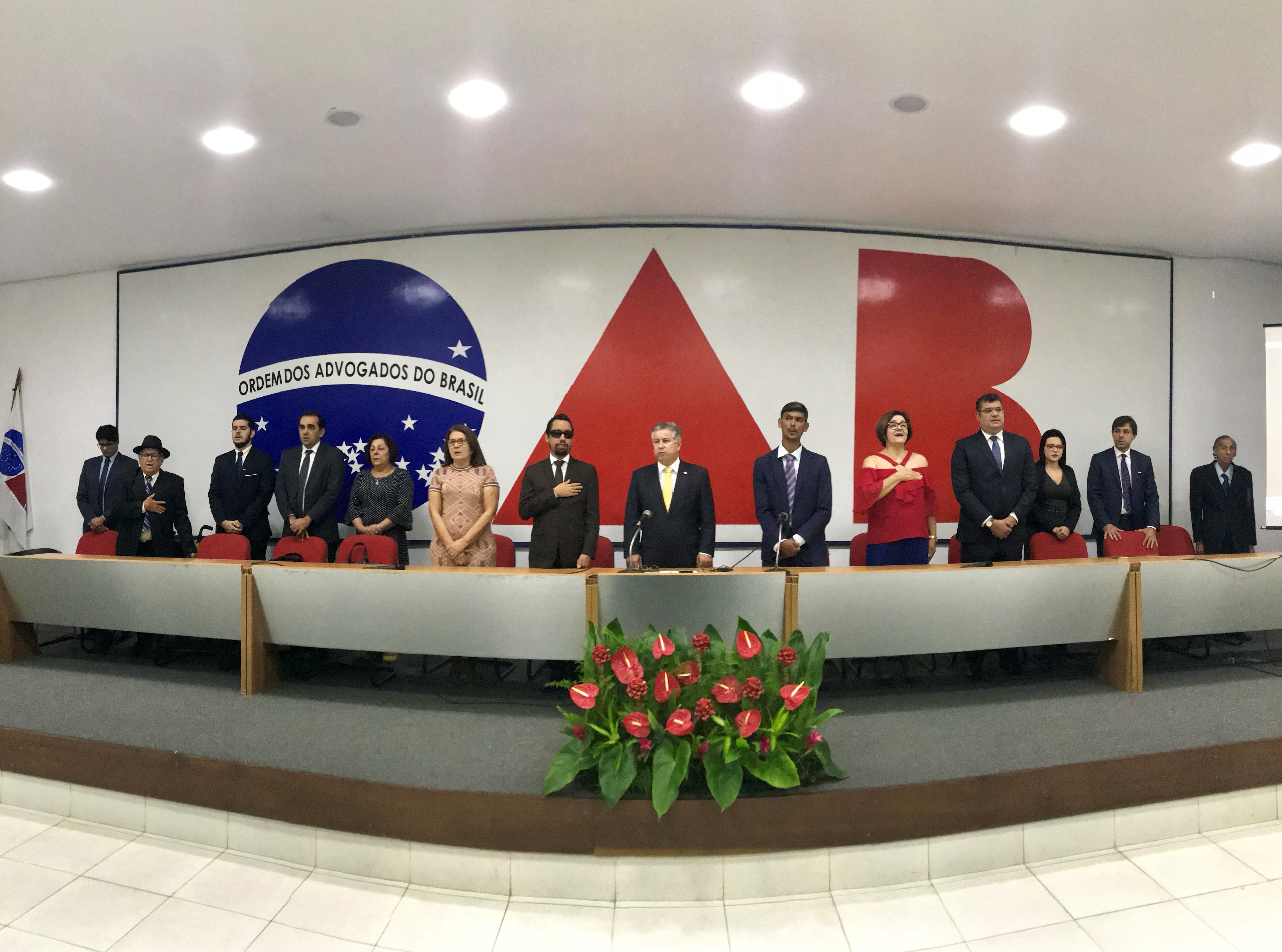 #PraCegoVer - Perfiladas, autoridades e palestrantes acompanham a execução do hino nacional