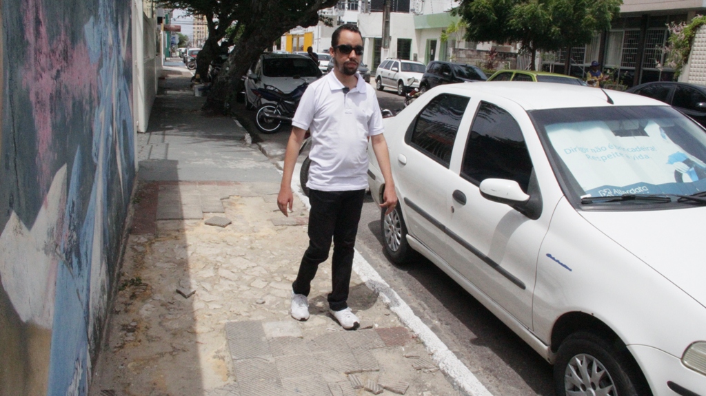 #PraCegoVer O vereador Lucas Aribé em uma calçada deteriorada e sem acessibilidade no centro da capital 