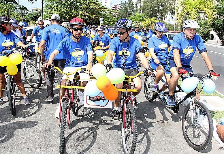 #PraCegoVer - Imagem de pessoas com camisa temática do passeio ciclístico Pedalando sem Barreiras pedalando juntas. À frente, Lucas Aribé e outra pessoa pedalam numa ODKV.