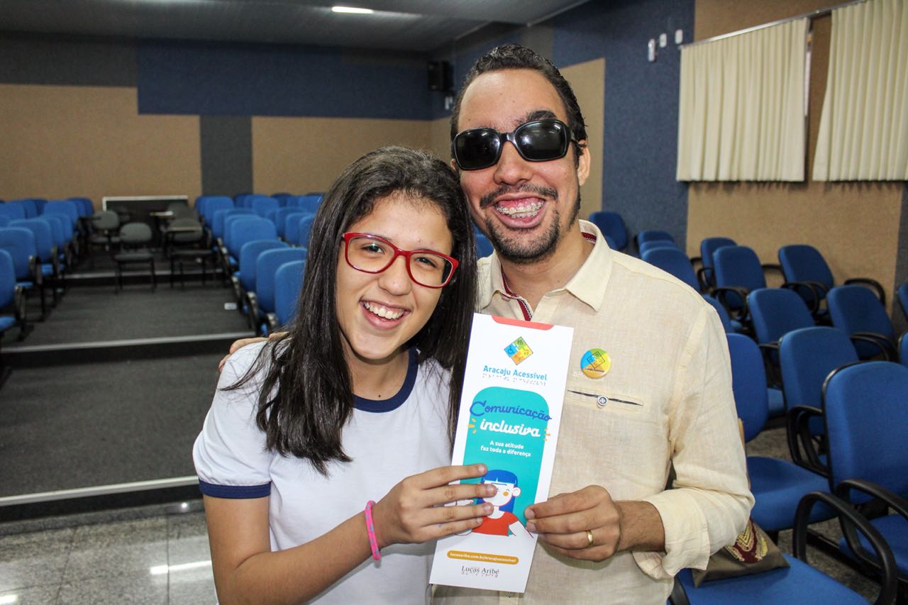 #PraCegoVer: Lucas entrega cartilha à estudante Mariana Laysa