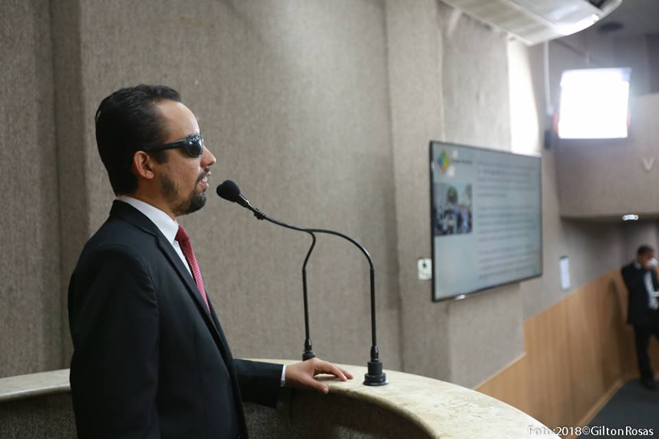 #PraCegoVer: A foto mostra o vereador Lucas Aribé falando no microfone da tribuna da Câmara e no telão do plenário mostra os slides da Semana Aracaju Acessível