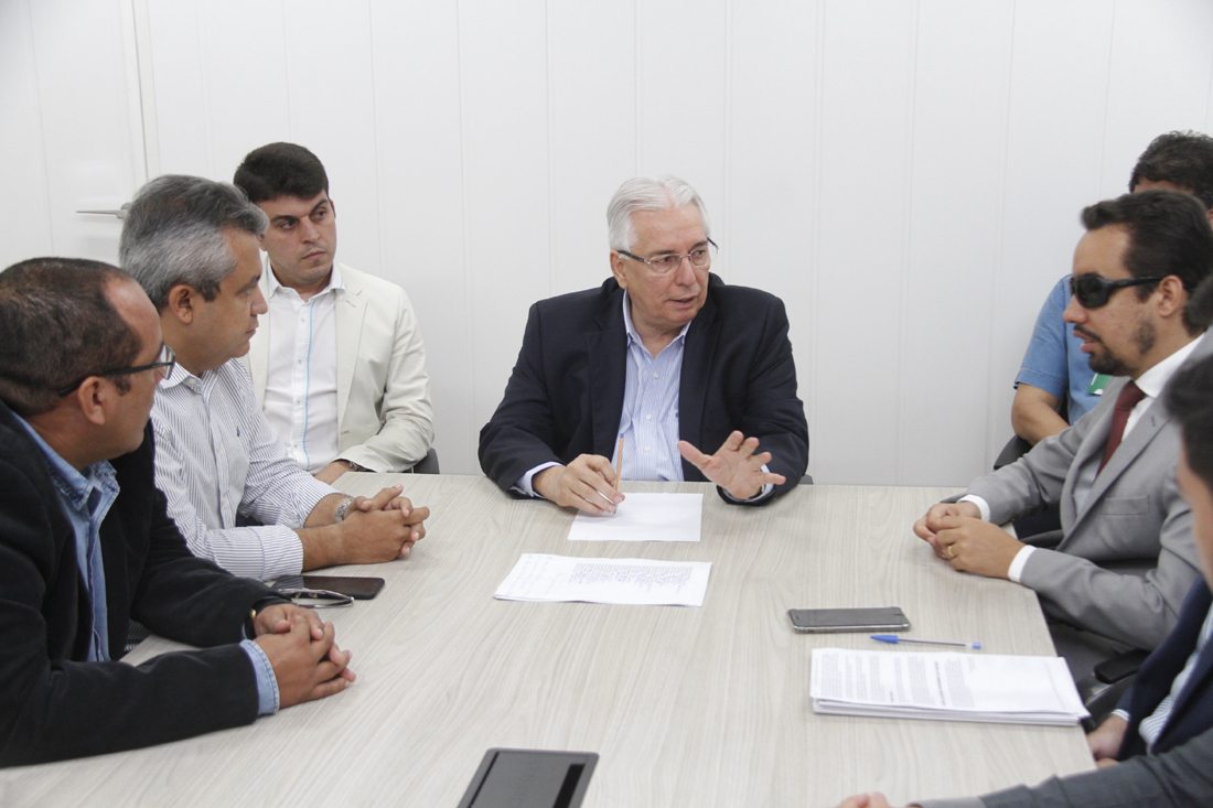 #PraCegoVer: O vereador Lucas Aribé e os outros vereadores e assessores estão sentados em uma mesa redonda conversando com o conselheiro do Tribunal de Contas, Luiz Augusto Carvalho Ribeiro