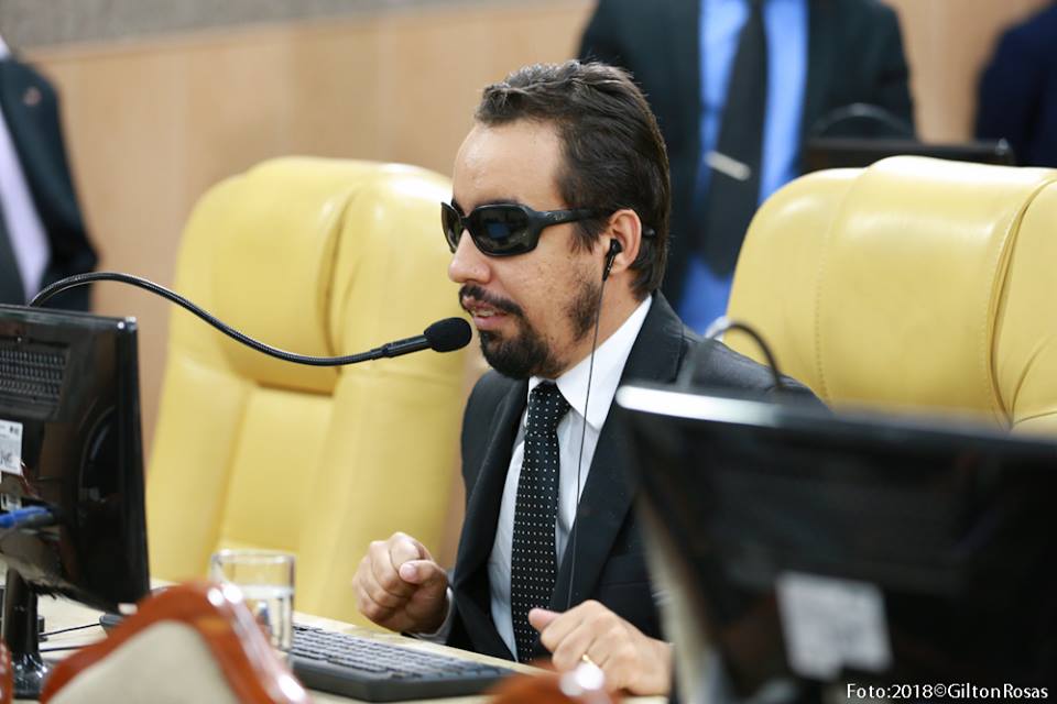 #PraTodoMundoVer: O vereador Lucas Aribé está sentado na sua cadeira falando ao microfone