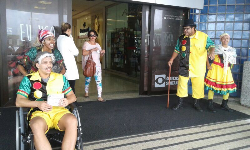 Grupo de teatro da SMTT está na porta do shopping encenando com tema da campanha. Na foto, dois atores em cadeiras de rodas representam idosos e deficientes