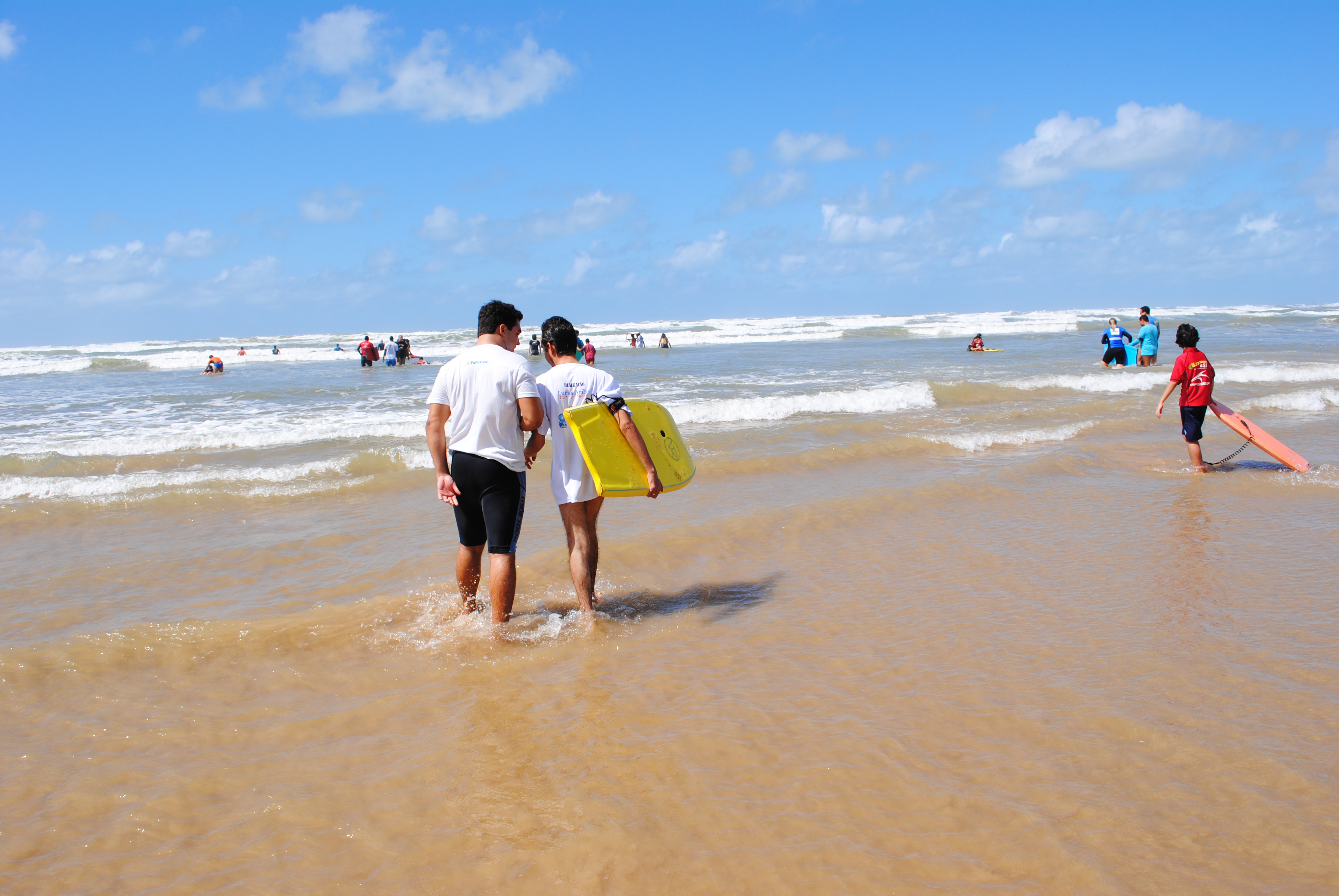 Hora de surfar: Aribé é acompanhado pelo instrutor Lucas na ida para o mar
