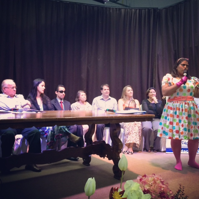 Foto da mesa formada para a solenidade. À frente, a professora Maria de Fátima faz uma apresentação