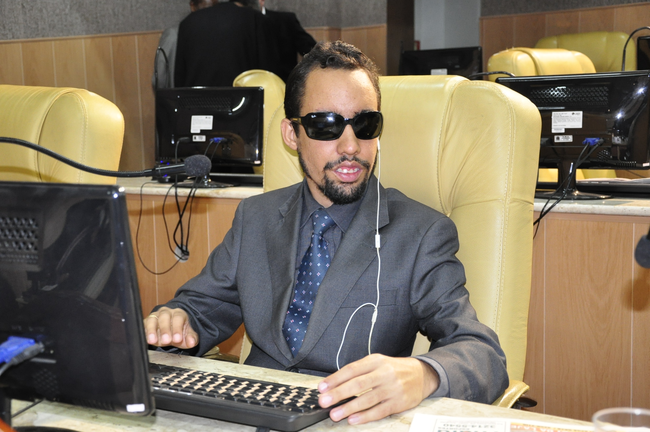 Lucas sentado no Plenário e está à frente do monitor do computador
