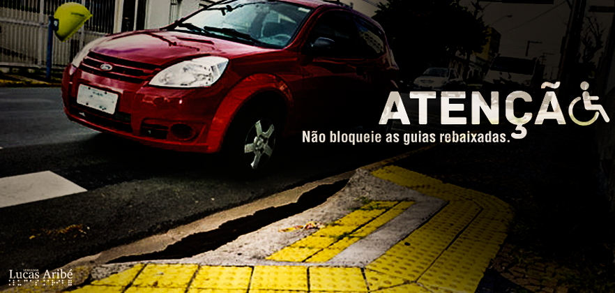 Imagem de um carro vermelho estacionado na rua e em frente a uma guia rebaixada